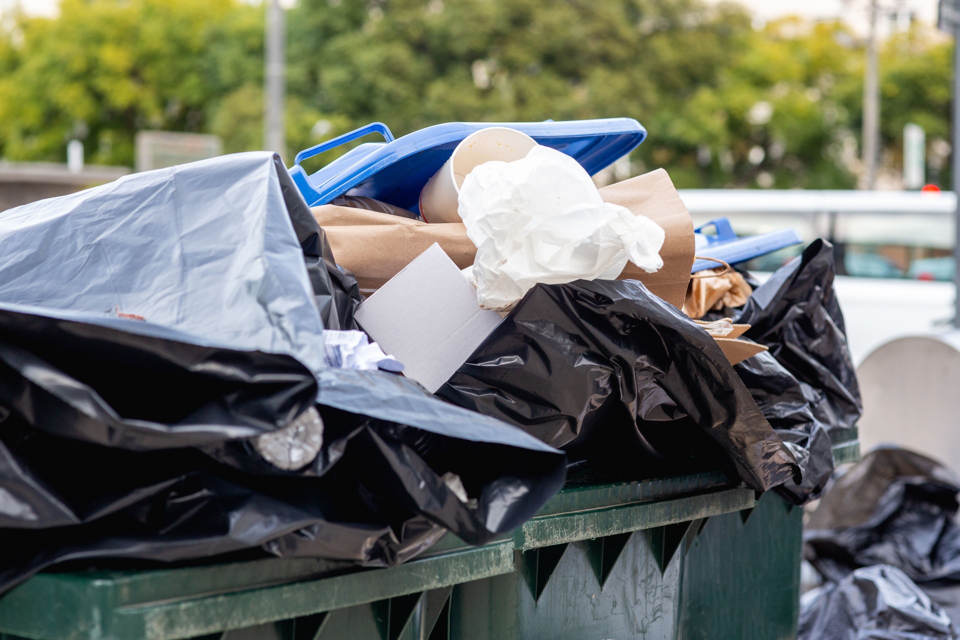 A pile of uncollected garbage in bags and trash bins on a European street. black plastic garbage bags.